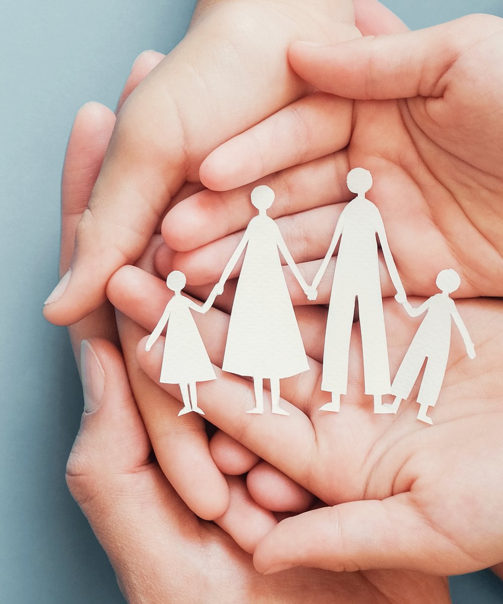 Layered hands cradling a paper family cut-out — supportive family therapy on the Gold Coast